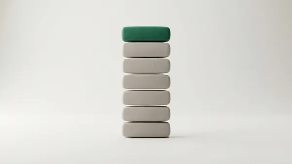 Seven rounded clay tiles stacked in a column, six grey and the top one green
